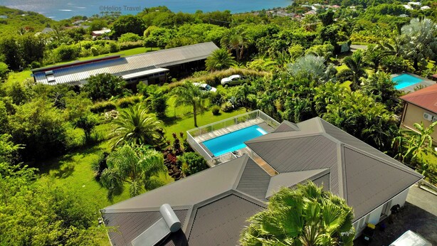 A resort with a swimming pool, lush greenery, and a view of the ocean. - Villa Tropical Quintet. 3 bedrooms. Sea view. Pool. Leroux beach at 800 m. (Deshaies)