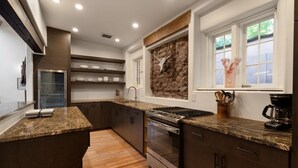 A modern kitchen with granite countertops, stainless steel appliances, and a stone backsplash.