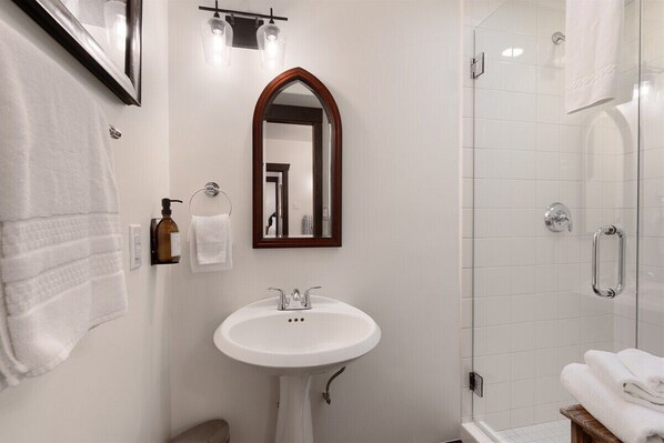 A bathroom with a pedestal sink, a mirror, a shower, and a towel rack. - Marcy House - Downtown East Side- 3 Bedroom (Santa Fe)