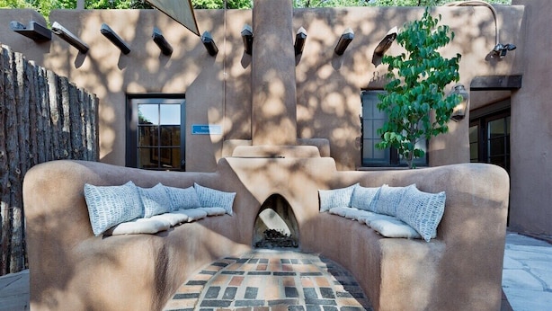 Un espacio al aire libre con una chimenea, paredes de piedra y un árbol.