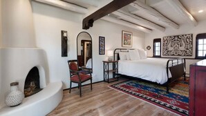 Un dormitorio con cama, una silla, chimenea y un tapiz grande.
