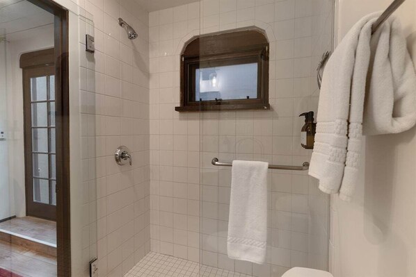 Un baño con ducha, ventana y perchero.