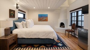 Ein Schlafzimmer mit Bett, Sessel, Fernseher, Kamin und einem Bild an der Wand.
