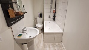 Et moderne badeværelse med vask, toilet og badekar.