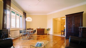 A spacious living room with a wooden floor, a glass dining table, and dark leather sofas. - Elegant Apartment in the Center by Wonderful Italy (Sanremo)
