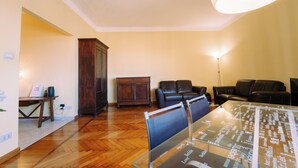 A living room with a wooden floor, two leather sofas, a glass coffee table, and a dark wooden cabinet. - Elegant Apartment in the Center by Wonderful Italy (Sanremo)