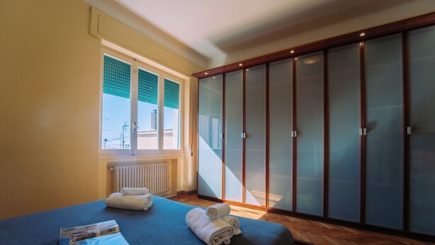 A bedroom with a bed, a window, a radiator, and a wardrobe. - Elegant Apartment in the Center by Wonderful Italy (Sanremo)