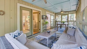 A covered porch with a ceiling fan, a dining table with chairs, and a sofa with cushions. - Seabrook Exclusives | 1138 Summerwind (Johns Island)