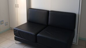 A room with a black sofa, a white wardrobe, and a tiled floor. - Sea view with no road to cross  (Leucate)