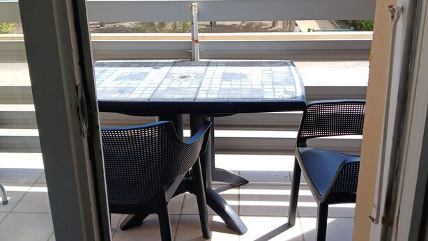 An outdoor patio with a table and chairs, a railing, and a view of trees and buildings. - Sea view with no road to cross  (Leucate)
