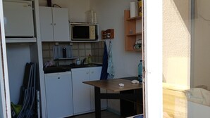 A compact kitchen with white cabinets, a microwave, a sink, and a small table. - Sea view with no road to cross  (Leucate)