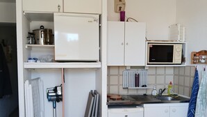 A compact kitchen with white cabinets, a microwave, a refrigerator, and a sink. - Sea view with no road to cross  (Leucate)