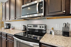 A kitchen with a stainless steel microwave, oven, and stove. There are cabinets above the counter and a coffee maker on the counter.