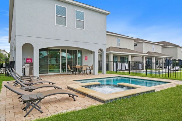 A residential building with a swimming pool, outdoor seating, and a barbecue area.