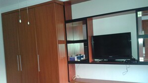 Ein Zimmer mit einem Holzschrank, einem Schminktisch mit Spiegel und einem Fernseher.