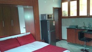 Ein Hotelzimmer mit Bett, Kühlschrank, Mikrowelle, Spüle und einer Barzeile.