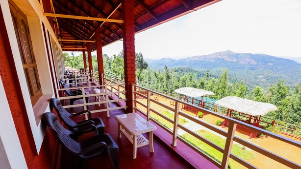 A balcony with seating and a view of a mountainous landscape. - Uttunga Homestay (Mudigere)