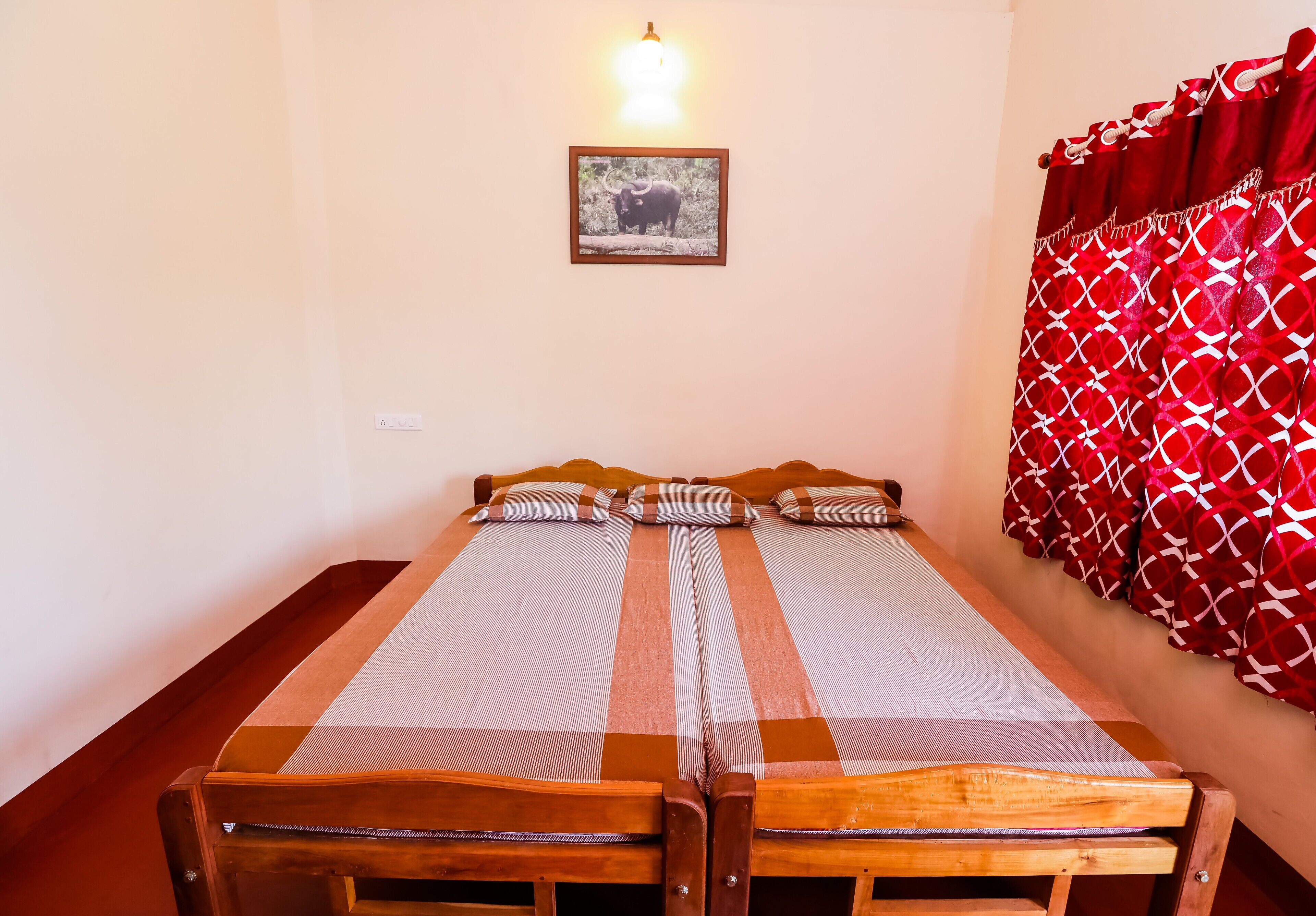 A double bed with a striped bedspread, a wall-mounted light, and a framed picture of an elephant.