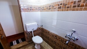 A bathroom with a toilet, a shower, and a tiled floor. - Uttunga Homestay (Mudigere)