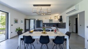 A modern kitchen with a central island, white cabinetry, and a dining area with a white table and black chairs.