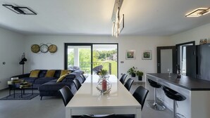 A modern kitchen with a dining area, a bar, and a sofa.