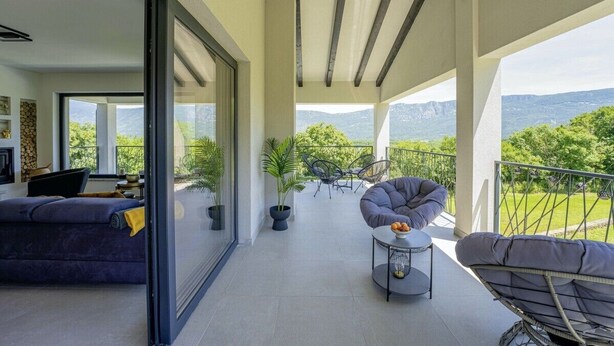 A balcony with a sofa, chairs, and a small table.