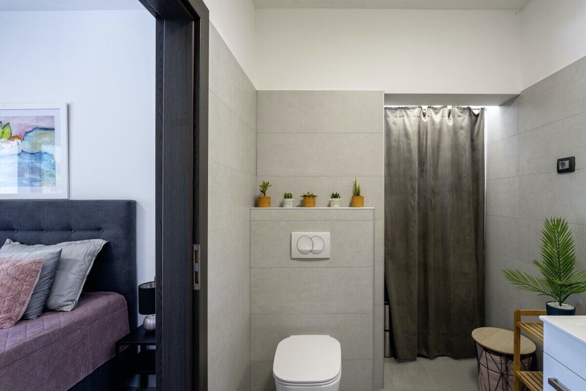 Ein modernes Badezimmer mit Toilette, Dusche und einem kleinen Tisch mit einer Pflanze.