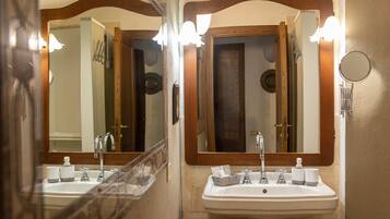 A bathroom with two sinks, a mirror, and a shower.