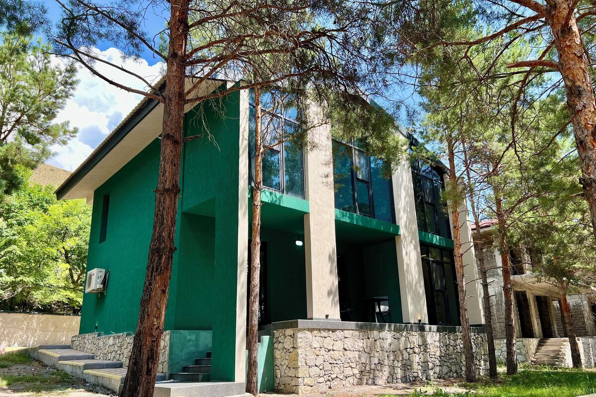 A modern building with a green facade, stone steps, and a stone wall.