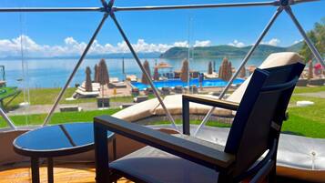 A glass-enclosed room with a view of a pool and lounge chairs.