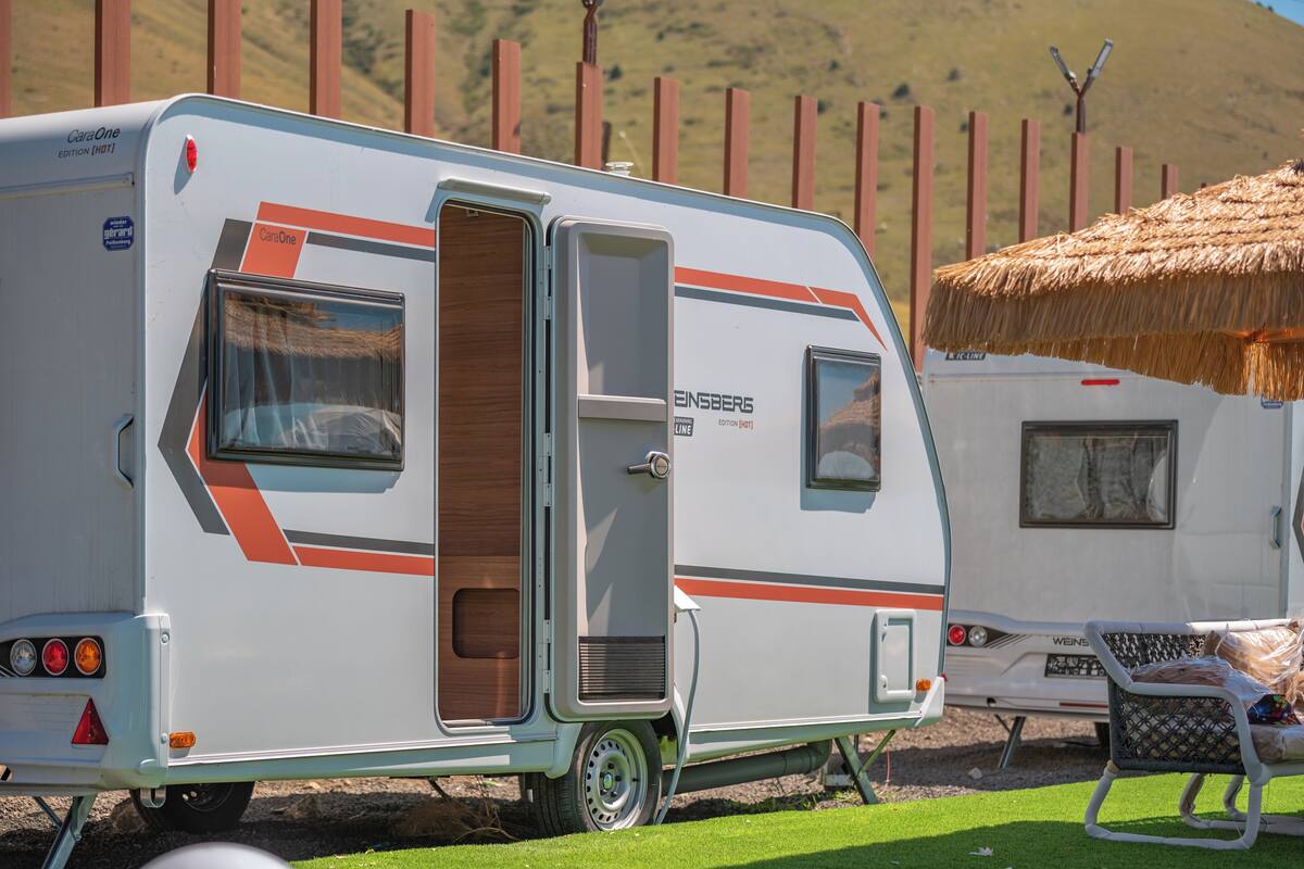 A caravan with a wooden door, a window, and a luggage rack.