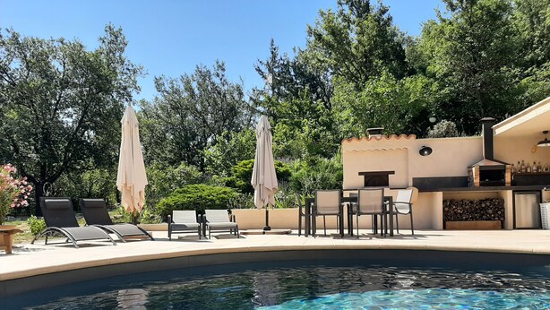 A swimming pool with clear water, surrounded by lounge chairs and umbrellas, and a barbecue area with a chimney. - Bed &breakfast in a peaceful natural setting swimming pool guaranteed relaxation (Dauphin)