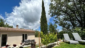 A house with a tiled roof, a patio with a table and chairs, a tall tree, and a garden with a bench. - Bed &breakfast in a peaceful natural setting swimming pool guaranteed relaxation (Dauphin)