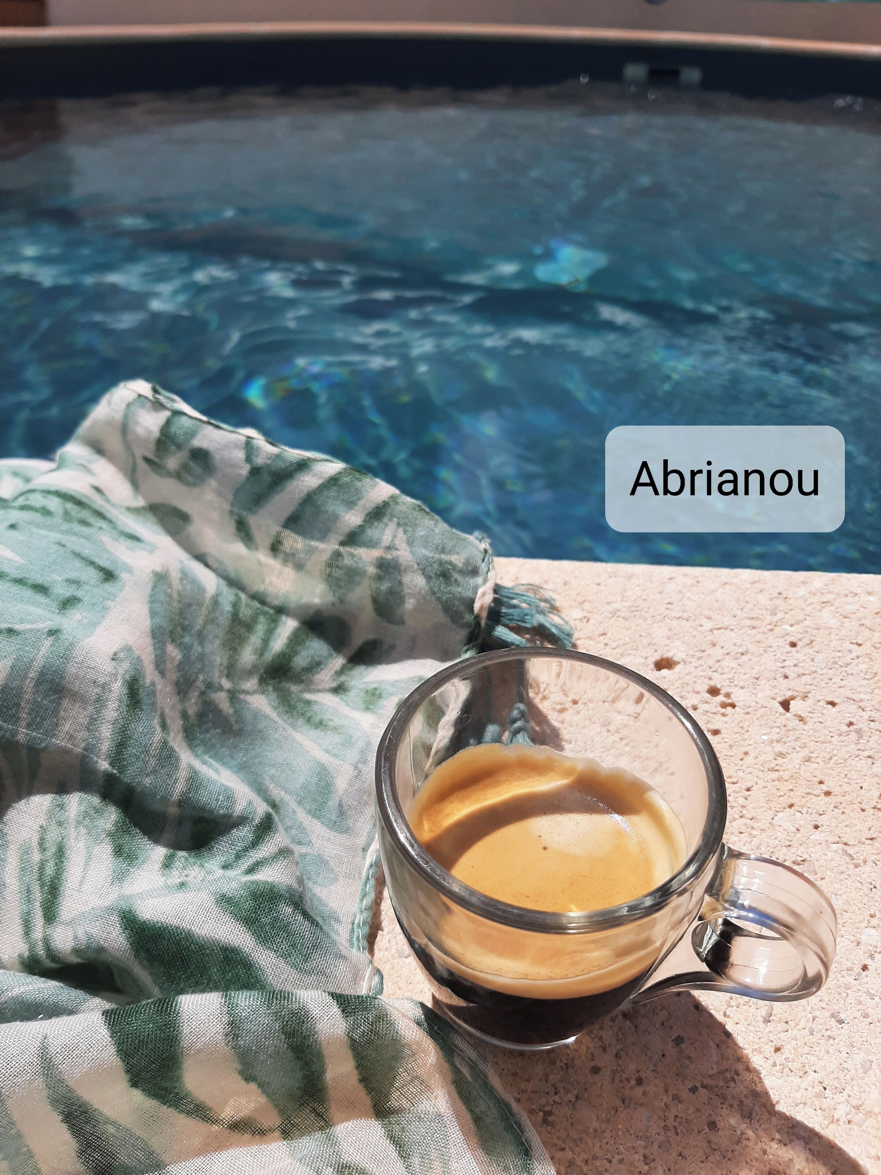 Une tasse de café sur une table, avec une piscine en arrière-plan.