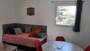 A small, modern room with a bed, a table, and a round dining table with chairs. - Bed &breakfast in a peaceful natural setting swimming pool guaranteed relaxation (Dauphin)