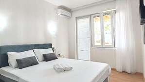 Een moderne slaapkamer met een groot bed, witte lakens, een donkere hoofdbord en een raam met gordijnen.