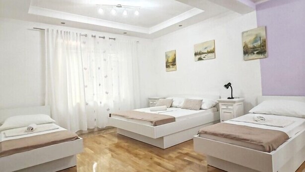 A modern bedroom with two beds, a large window with curtains, and a wooden floor. - Apartments Lucerna / Comfort 3 apartment for 4 people (Neum)