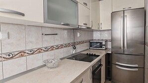 A modern kitchen with white cabinets, a stainless steel refrigerator, a microwave, and a gas stove. - Apartments Lucerna / Comfort 3 apartment for 4 people (Neum)