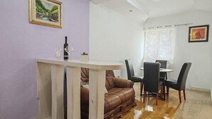 A dining area with a table and chairs, a sofa, and a painting on the wall. - Apartments Lucerna / Comfort 3 apartment for 4 people (Neum)