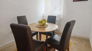 A dining area with a round table, four chairs, a bowl of fruit, and a window with blinds. - Apartments Lucerna / Comfort 3 apartment for 4 people (Neum)