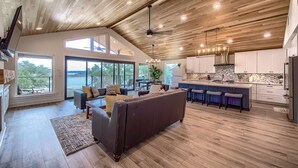 A spacious living area with a large brown sofa, a dining table, and a kitchen with a bar. - Cl 874 Million Dollar View 5 Bedroom Home by RedAwning (Canyon Lake)