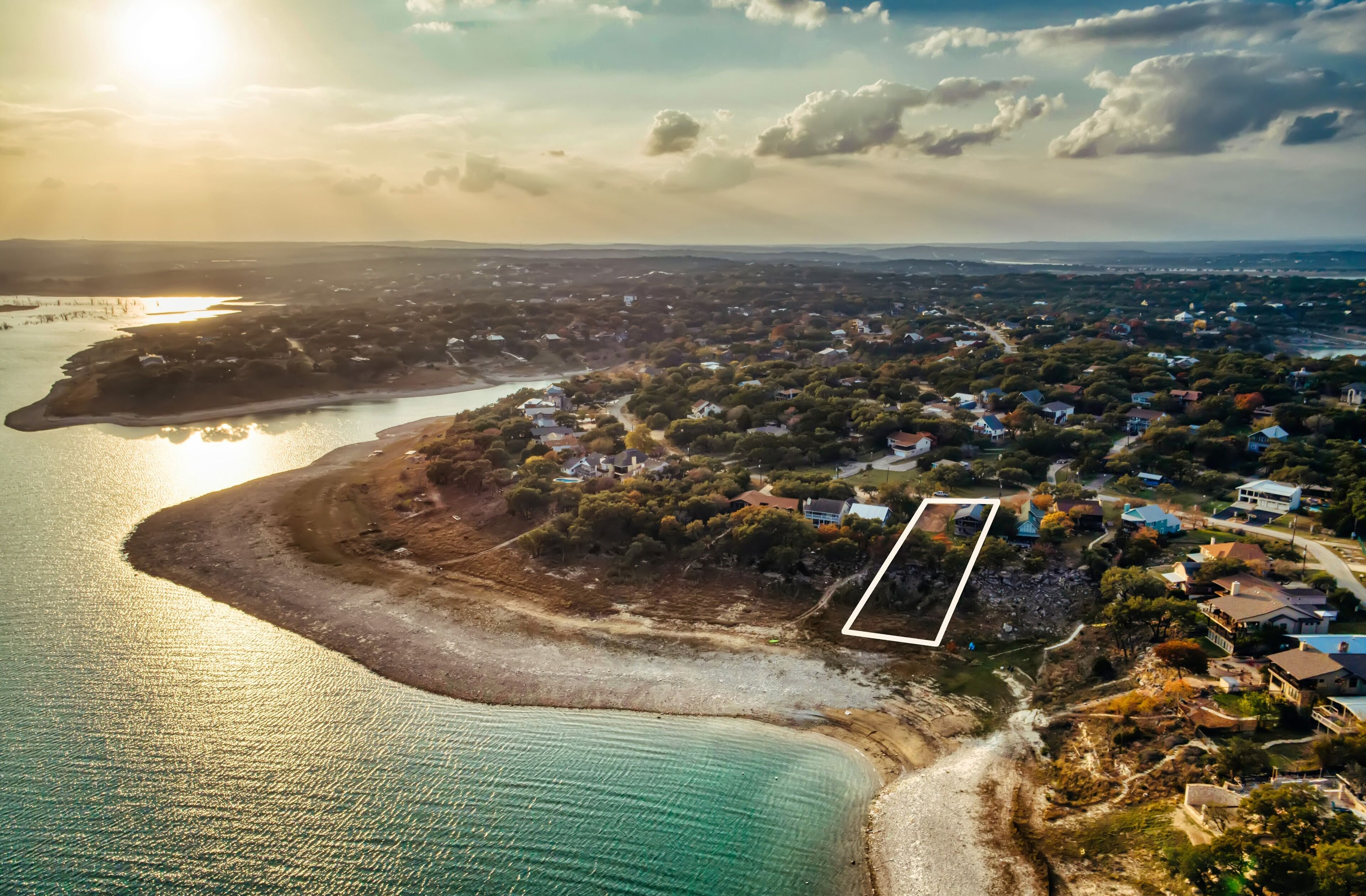 An aerial view of a coastal area with a beach, houses, and a river.