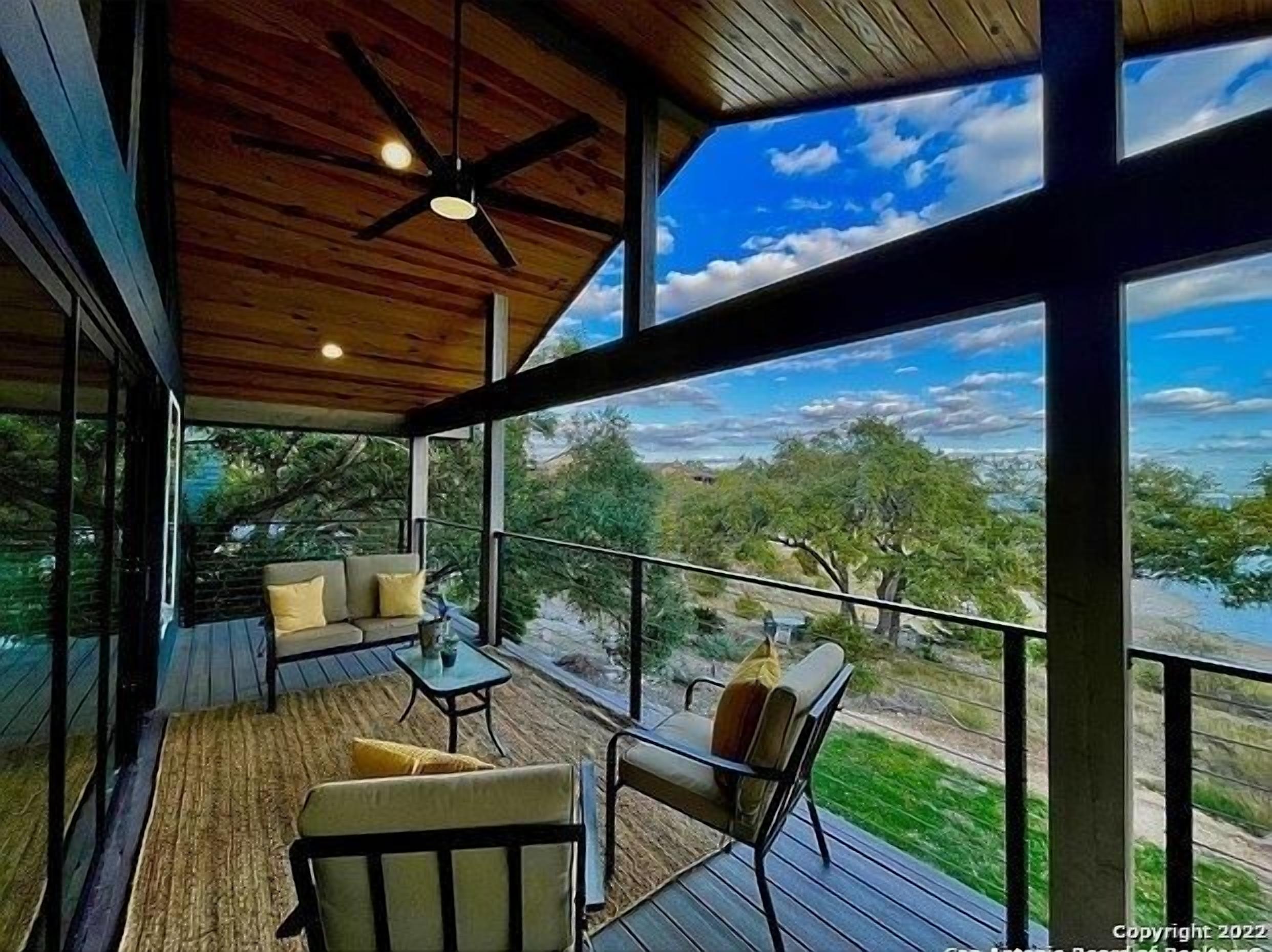 Un espacio al aire libre cubierto con techo de madera, ventilador de techo y vista a un paisaje natural.