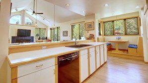 A modern kitchen with a dishwasher, a sink, and a dining area with a table and chairs.