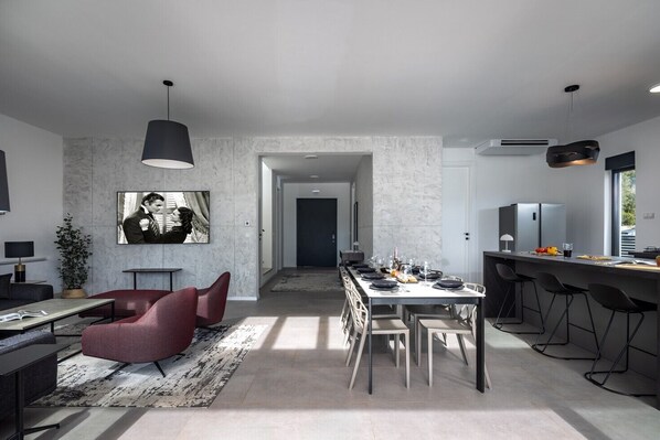 Una cocina moderna con una larga mesa de comedor, taburetes de bar y un amplio ventanal.