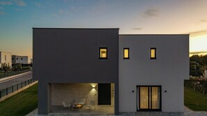Un edificio moderno de dos pisos con techo plano, ventanas amplias y un interior bien iluminado.
