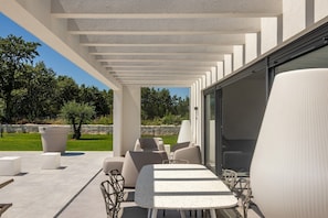 Relax under a shaded pergola with comfortable seating and lush surroundings.