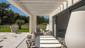 Un patio al aire libre con una zona de estar techada, una mesa y sillas.