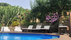 Un área de piscina con sillones reclinables y una pared de piedra.