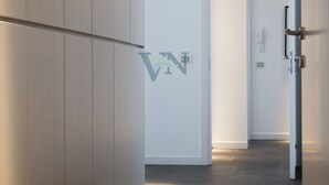 A modern hallway with a wooden cabinet, a door with a phone, and a tiled floor.